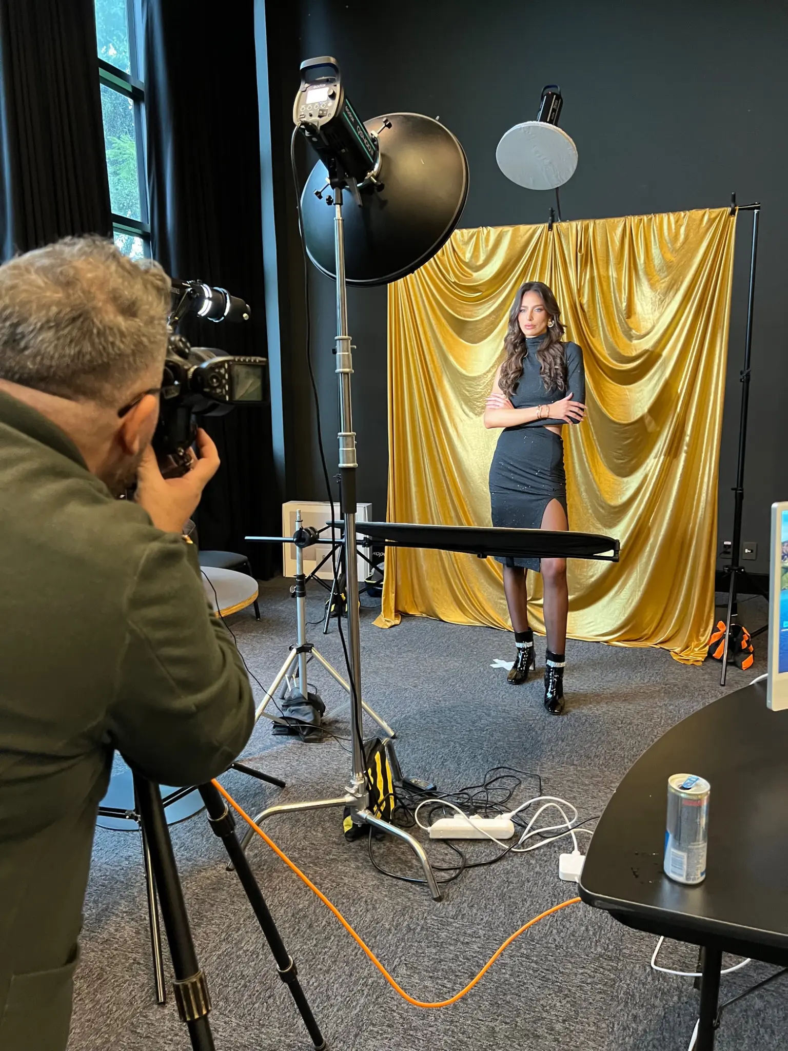 Antares Martins fotografando uma modelo em produção com fundo dourado